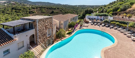 A swimming pool surrounded by buildings with a view of the countryside.