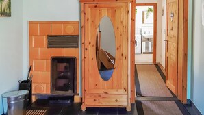 Una puerta de madera con un ventanal pequeño, una chimenea con azulejos y un cubo de metal.