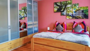Un dormitorio con cama, un armario y tres cuadros en la pared.