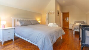 A bedroom with a bed, bedside tables, a nightstand, a wooden door, and a small desk with a chair. - Relaxing Private Country Escape with Hot Tub (Castlerea)
