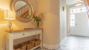 A hallway with a console table, wicker baskets, a mirror, and a vase with flowers. - Relaxing Private Country Escape with Hot Tub (Castlerea)
