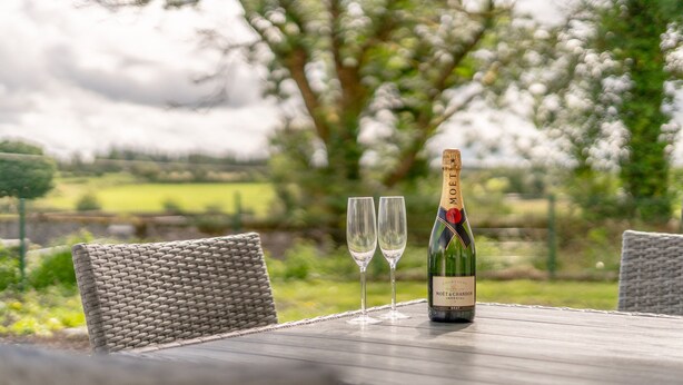 A bottle of Moët & Chandon champagne with two glasses on a table outdoors. - Relaxing Private Country Escape with Hot Tub (Castlerea)