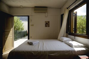 Ein Schlafzimmer mit einem Bett, einem Fenster und einer offenen Tür, die auf einen Balkon führt.