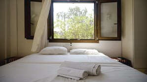 A bedroom with a bed, two windows, and a view of trees. - Apartment for 3 pax | Bellino Apartments (Chersonissos)