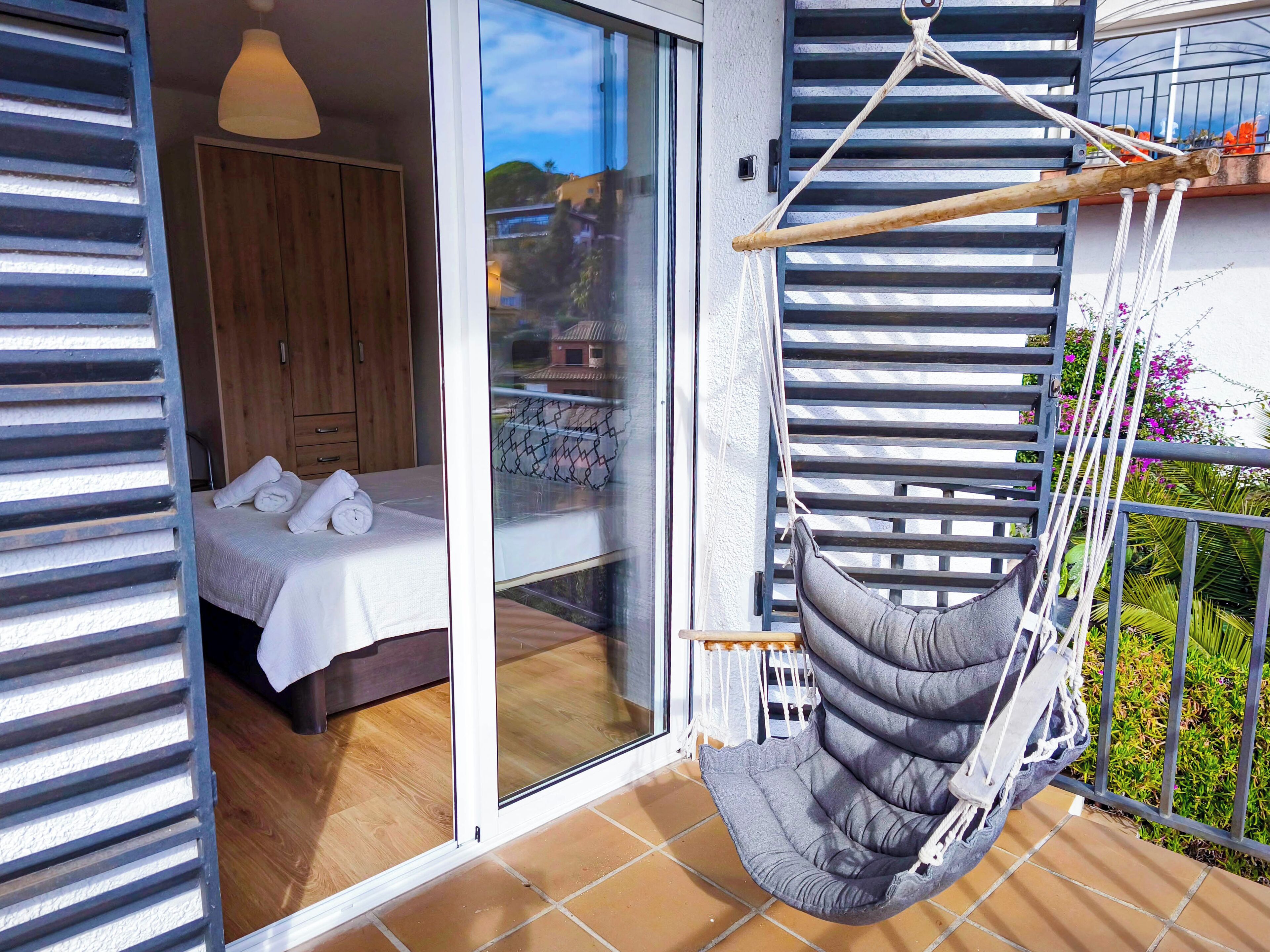 Una habitación con cama, una silla colgante y vistas al exterior.