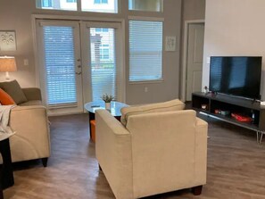 Relax in this inviting living room with a sofa, coffee table, and flat-screen TV, plus a sliding door to an outdoor area.