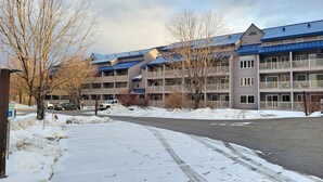 Un hotel de varios pisos con techo azul, un estacionamiento cubierto de nieve y un cielo despejado.