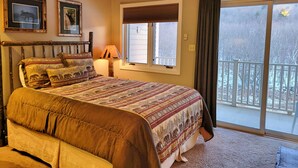 Un dormitorio con una cama grande, una ventana con persianas, una lámpara y vistas a un paisaje nevado.