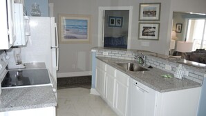 A modern kitchen with white cabinets, a granite countertop, a stainless steel sink, and a dishwasher.