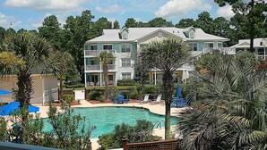 A resort with a swimming pool, multiple-story buildings, and outdoor seating areas.