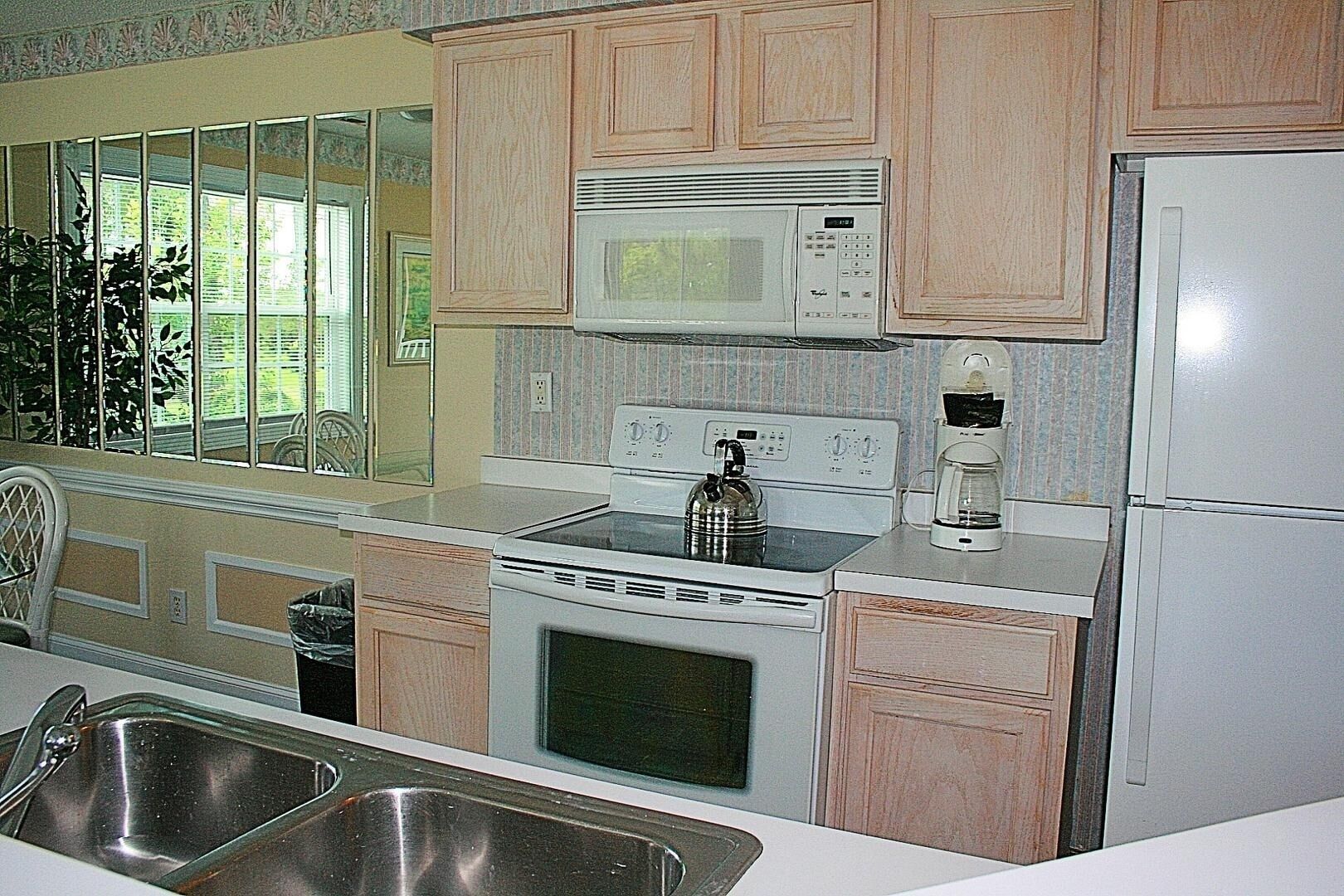 A kitchen with wooden cabinets, a microwave, a stove, a refrigerator, and a sink.