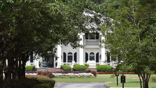 A white building with arched windows and a balcony, surrounded by well-maintained gardens and a paved driveway. - Studio Villa 509L at Brunswick Resort and Golf with Outdoor Pool and Beaches Nearby by RedAwning (Calabash)
