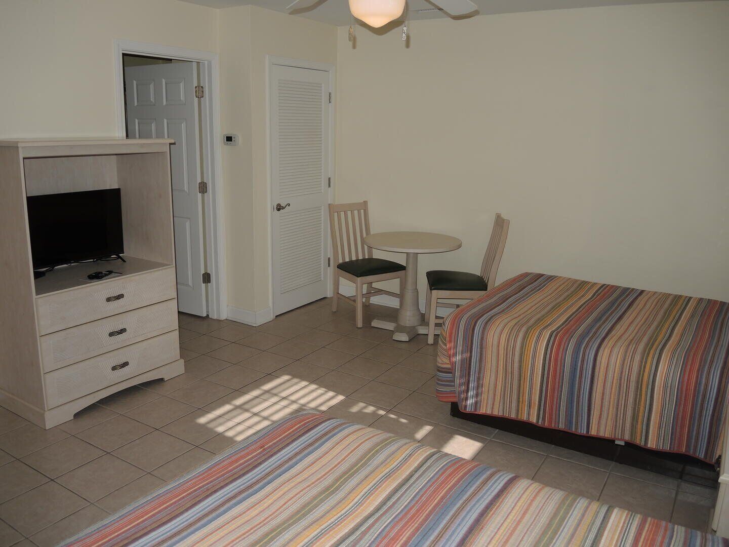 A bedroom with a bed, a desk, a chair, and a television.