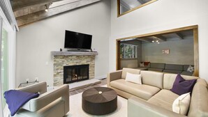 Un salon moderne avec une cheminée, un grand miroir et un téléviseur.