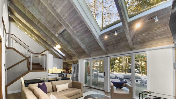 Un vaste espace de vie au design moderne, comprenant un grand canapé, une table basse et une porte vitrée donnant sur un balcon.