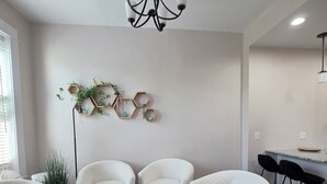 A modern living room with white sofas, a coffee table, and a hexagonal wall decoration. - Summer Fling 2nd Floor Downtown Suite  (South Haven)