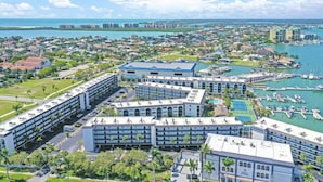 Un hôtel à plusieurs étages doté d’un parking souterrain, d’un port de plaisance avec des bateaux et offrant une vue sur la côte.