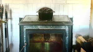 A rustic kitchen with a vintage stove, a white brick fireplace, and three wall-mounted lanterns. - Adirondack Retreat - Hot Tub & Lake (Keeseville)