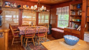 A wooden cabin interior with a dining table, chairs, a chandelier, and a large blue bowl on a wooden table. - Adirondack Retreat - Hot Tub & Lake (Keeseville)