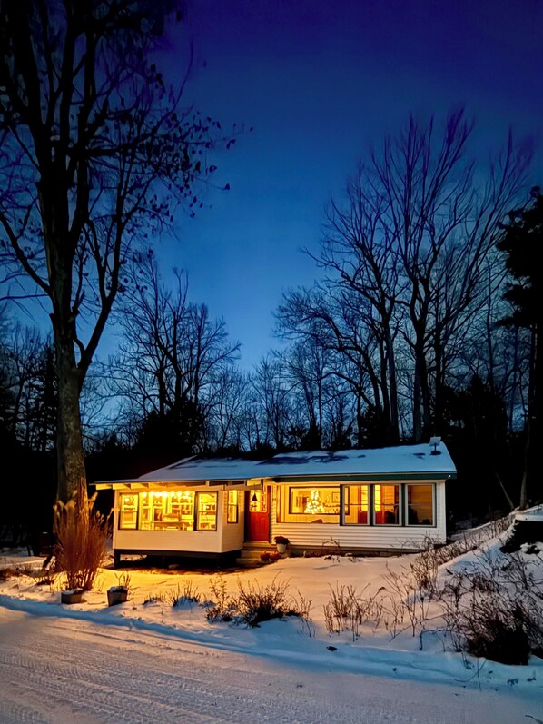 A modern house with a flat roof, large windows, and a snow-covered driveway.