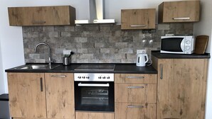 Una cocina moderna con gabinetes de madera, estufa de acero inoxidable, horno empotrado, microondas y cafetera.