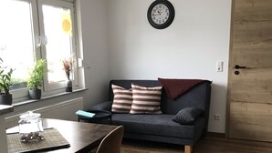 Un espacio habitable compacto con comedor, sofá, un reloj en la pared y una puerta de madera.