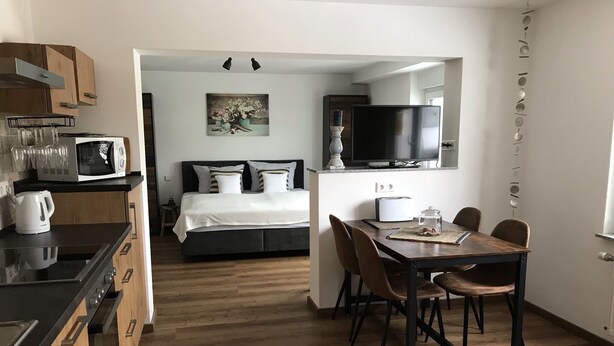 Una cocina compacta y moderna con comedor y un dormitorio.