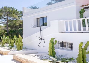 A modern building with a minimalist design, featuring a white exterior, a built-in window, and a small balcony.