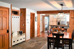 A wooden interior with a dining area, kitchen, and a sign indicating a lake house establishment. - Lake Front, Lake Charlevoix, Large Park like setting. (Boyne city)
