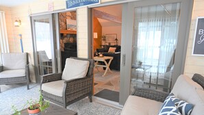 A cozy indoor seating area with wicker furniture, a potted plant, and a sign above the door. - Lake Front, Lake Charlevoix, Large Park like setting. (Boyne city)