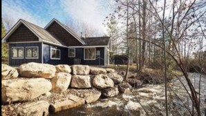 A two-story house with a stone retaining wall in front. - Lake Front, Lake Charlevoix, Large Park like setting. (Boyne city)