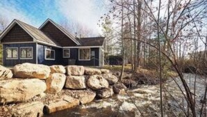 A two-story house with a stone retaining wall in front.