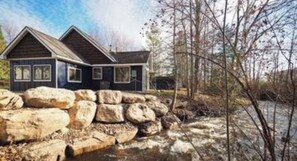 Une maison à deux étages avec un mur de soutènement en pierre à l’avant.