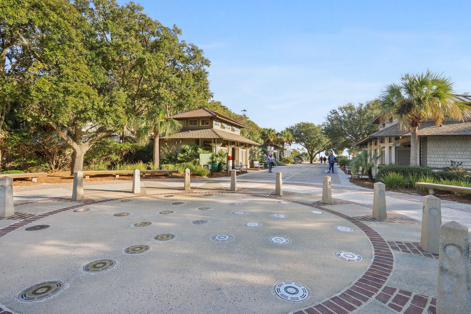 A courtyard with a building, trees, and a paved area with bollards.