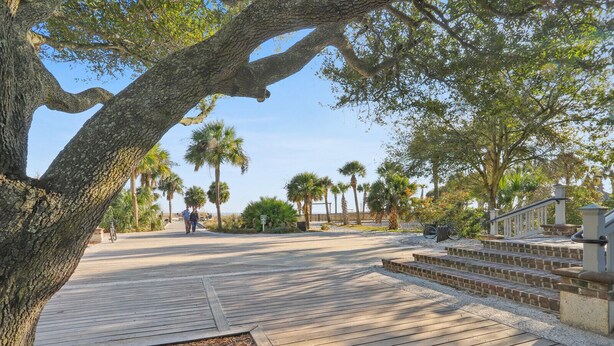 A wooden boardwalk leading to a beach with palm trees and a staircase.