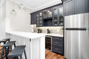 A modern kitchen with dark cabinets, a stainless steel refrigerator, and a white countertop.