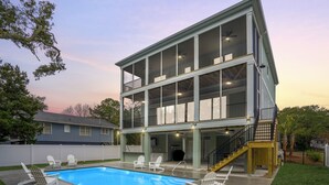 Ein zweistöckiges Haus mit Pool, Sitzgelegenheiten im Freien und einer überdachten Terrasse.