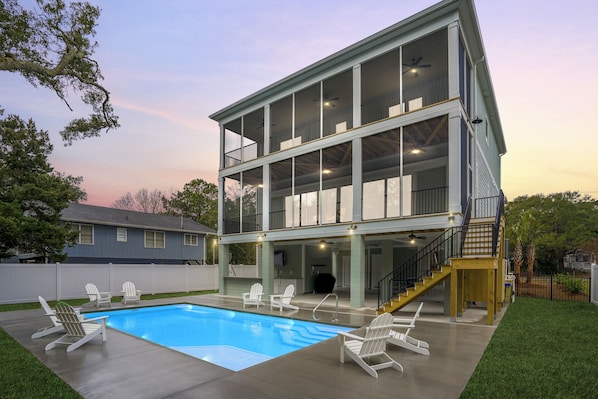 A two-story house with a pool, outdoor seating, and a covered patio area.