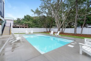 A rectangular swimming pool with a wooden deck and white lounge chairs. - Litchfield Home w/ Private Pool for Large Groups (Litchfield by the Sea)