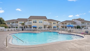 A swimming pool surrounded by a fence, with a building in the background. - Bring Your Pup! 2BR Near Beach Free Beach Service (Destin)