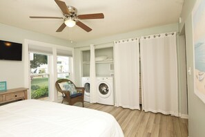 A bedroom with a bed, a ceiling fan, a washing machine, and a chair.