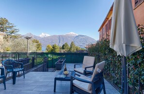A patio with outdoor furniture, a table with a bottle and glass, and a view of mountains.