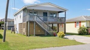 Une maison à deux étages avec un balcon, une terrasse en bois et un appareil de climatisation apparent.