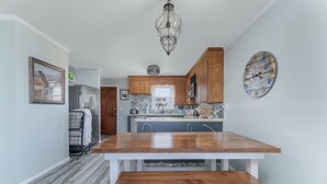 Une cuisine moderne avec une table en bois, des armoires blanches et un luminaire suspendu.