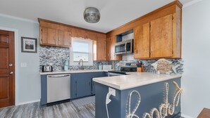 Une cuisine moderne avec des meubles en bois, un four à micro-ondes encastré et un grand îlot central doté d'une prise de courant.