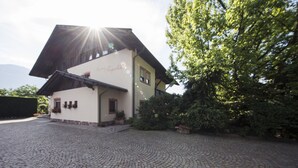 A building with a sloped roof, a cobblestone driveway, and a well-maintained garden.