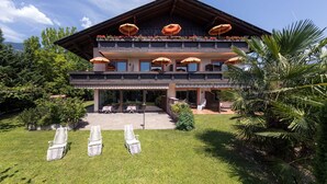 A two-story building with a balcony, outdoor seating area, and a well-maintained lawn.