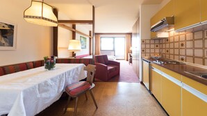 A compact hotel room with a dining area, a kitchenette, and a view of the outdoors.