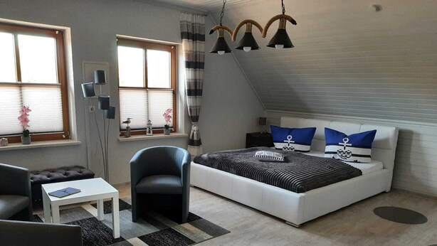 Um quarto moderno com uma cama grande, uma escrivaninha, uma cadeira e uma janela com cortinas.