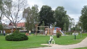 Um parque com parquinho, um caminho e um edifício ao fundo.